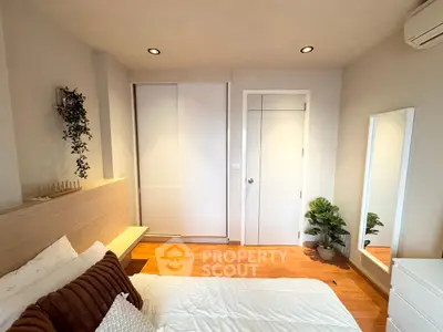 Cozy bedroom with modern decor, wooden flooring, and ample natural light.