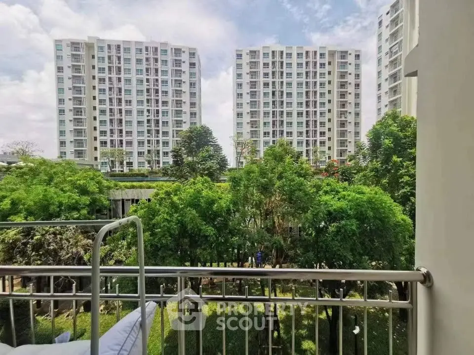 Stunning view from balcony overlooking lush greenery and modern high-rise buildings.