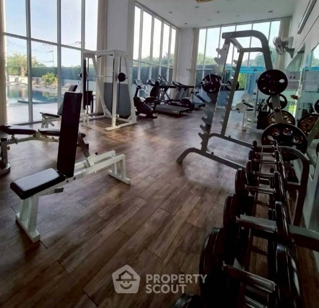 Spacious gym with modern equipment and large windows offering natural light.