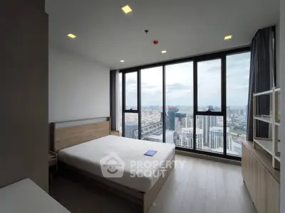 Spacious bedroom with floor-to-ceiling windows offering stunning city views, modern furnishings, and ample natural light.