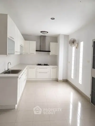 Spacious modern kitchen with sleek white cabinetry and gas stove