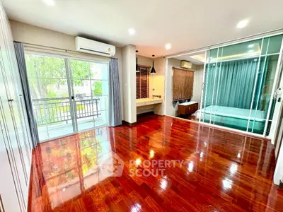 Spacious room with polished wooden floors and balcony access in modern apartment