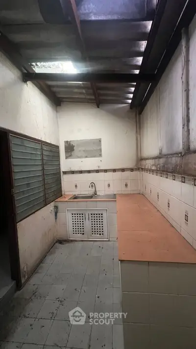 Spacious kitchen with tiled countertops and large window, ideal for renovation.