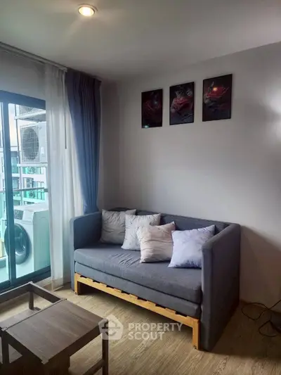 Cozy living room with modern decor and balcony view, featuring a comfortable sofa and stylish wall art.