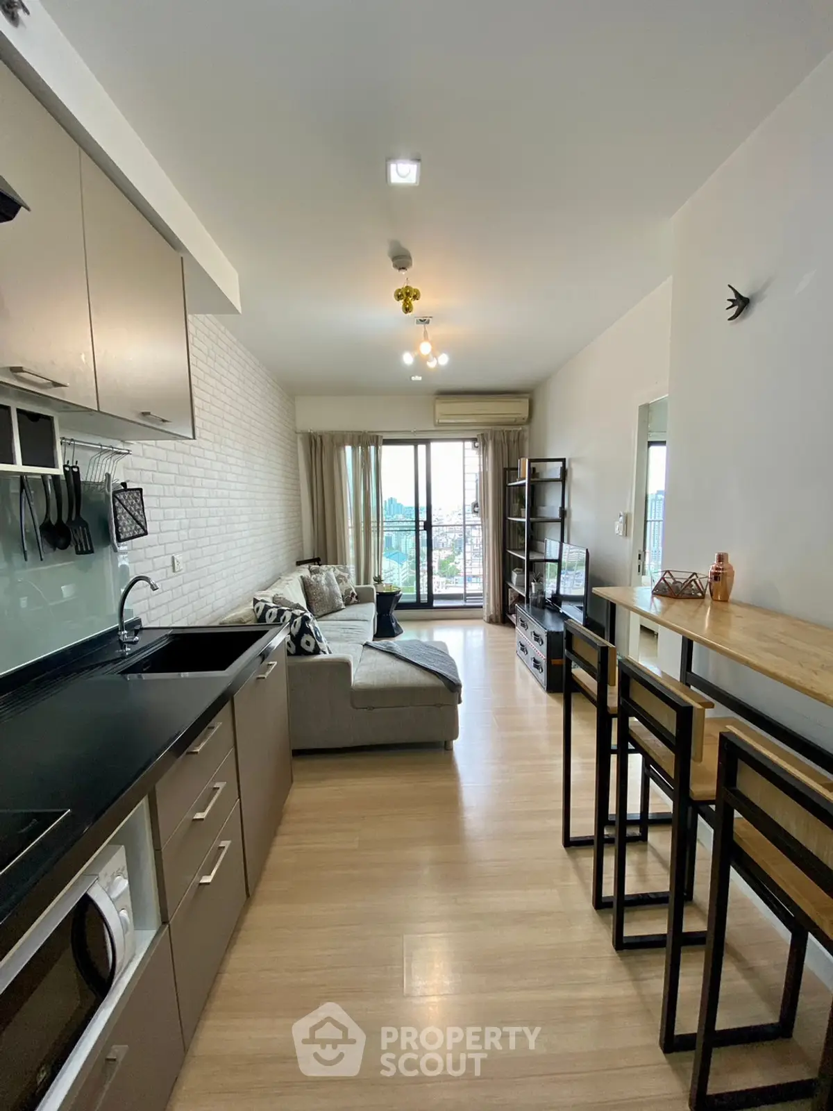 Modern open-plan living room with kitchen, featuring stylish decor and natural light.