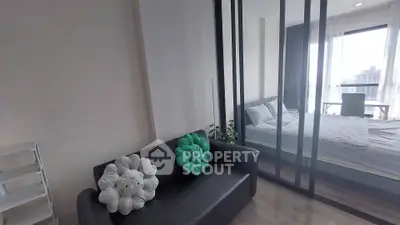 Modern studio apartment with cozy living area and bedroom, featuring large windows and stylish decor.