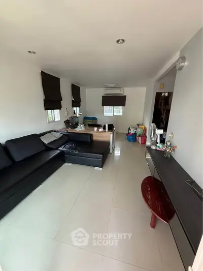 Spacious living room with modern black sofa and sleek decor, perfect for relaxation and entertainment.