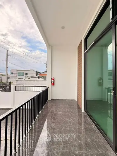 Spacious balcony with sleek glass doors and modern railing, offering a serene view of the neighborhood.