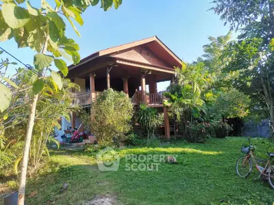 Charming wooden house with lush garden and tropical plants, perfect for serene living.