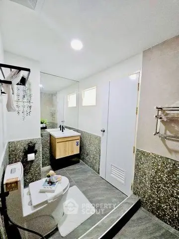 Modern bathroom with sleek design, featuring a large mirror and stylish fixtures.