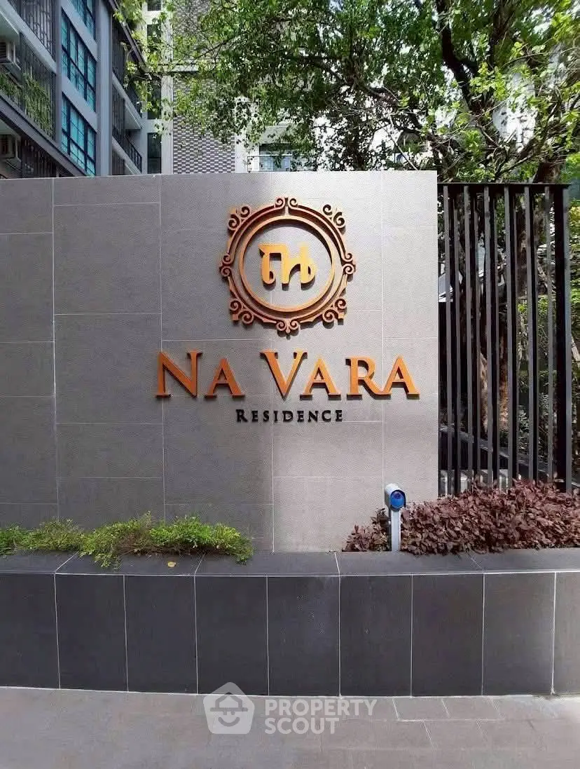 Elegant entrance sign of Na Vara Residence with modern design and lush greenery.