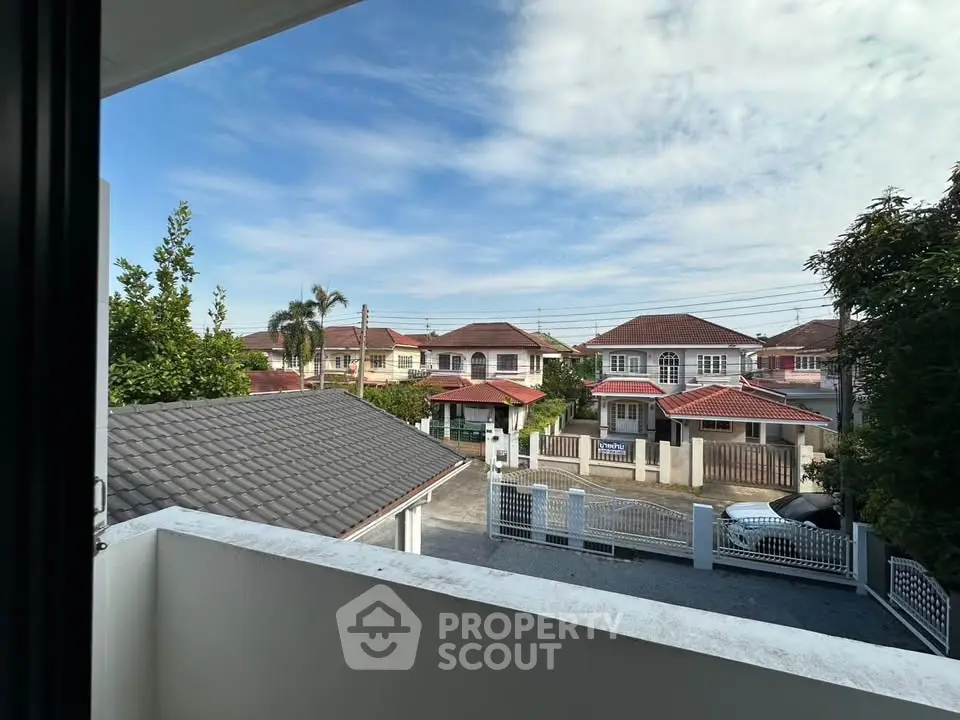 Charming suburban view from a balcony overlooking a peaceful neighborhood with lush greenery and clear skies.