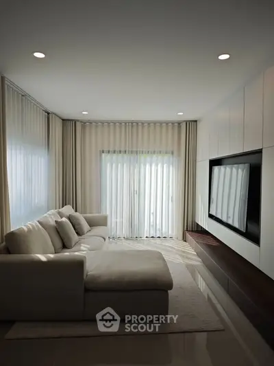 Modern living room with sleek design, featuring a large sectional sofa and built-in entertainment unit.