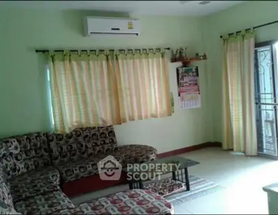 Cozy living room with patterned sofa, air conditioning, and natural light from large windows.