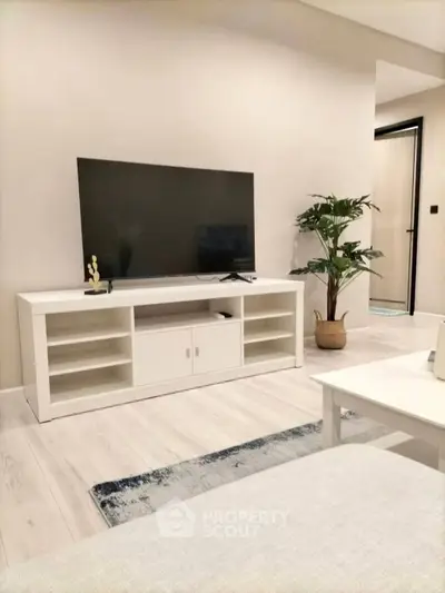 Modern living room with sleek TV stand and large flat-screen TV, complemented by stylish decor and cozy ambiance.