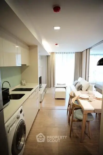 Modern open-plan living room with kitchen and dining area, featuring sleek design and natural light.