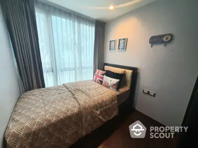 Cozy bedroom with a comfortable double bed, adorned with stylish pillows and a large window draped with sheer curtains, offering a serene living space.