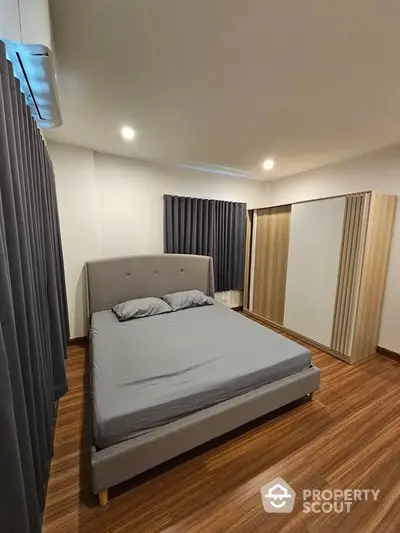 Modern bedroom with sleek design and wooden flooring, featuring a cozy bed and spacious wardrobe.