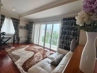 Spacious living room with elegant decor and large windows offering natural light and garden view.