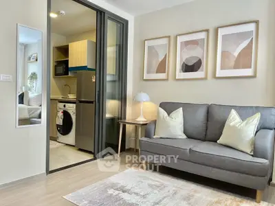 Modern living room with stylish decor and open kitchen layout, featuring a cozy sofa and contemporary artwork.