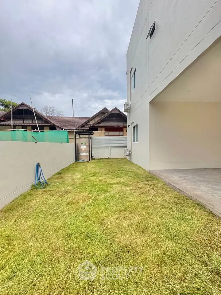 Spacious backyard with lush green lawn and modern building exterior, perfect for outdoor activities.