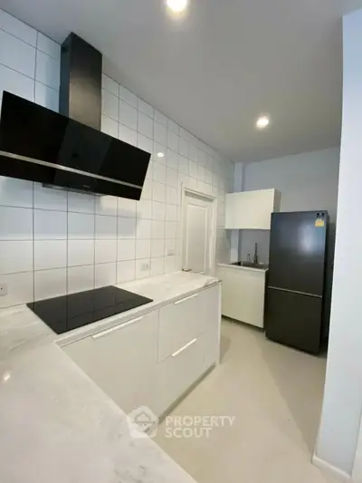 Modern kitchen with sleek white cabinets and black appliances in a minimalist design.