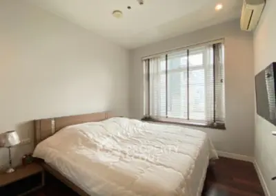 Cozy bedroom with large window and modern furnishings, perfect for relaxation.
