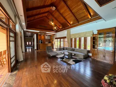 Luxurious living room with high wooden ceilings and elegant decor, featuring a spacious open layout and pool view.