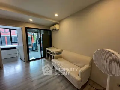 Modern living room with cozy sofa and air conditioning, featuring a view into a bright bedroom.