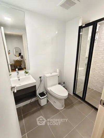 Modern bathroom with sleek fixtures and glass shower enclosure in contemporary apartment.