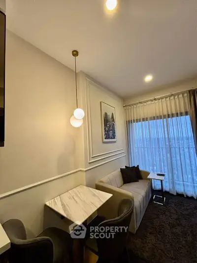 Elegant living room with modern decor and cozy seating area, featuring stylish lighting and large window view.