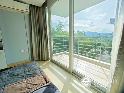 Bright bedroom with balcony and stunning view of lush greenery and mountains.