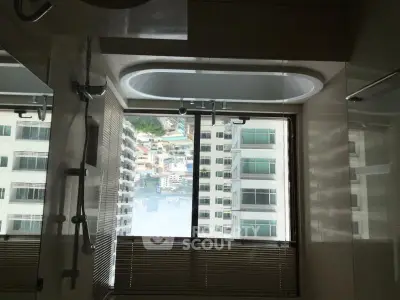 Luxurious bathroom with city view and modern bathtub in high-rise apartment.