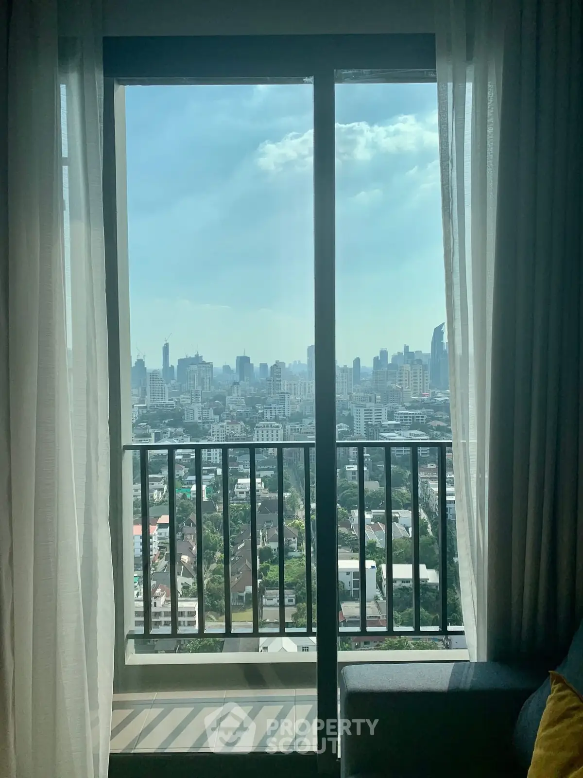 Stunning cityscape view from a modern apartment balcony with floor-to-ceiling windows.