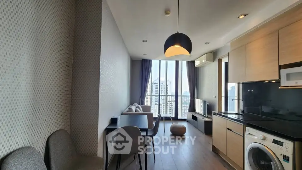 Modern living room with city view, open kitchen, and stylish decor in a high-rise apartment.