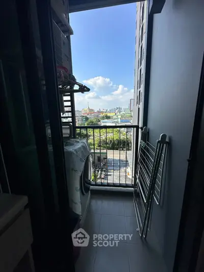Compact balcony with washing machine and city view, ideal for urban living.