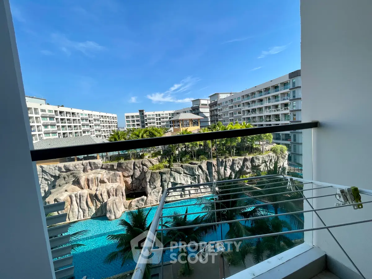Stunning balcony view of modern residential complex with pool and lush greenery.