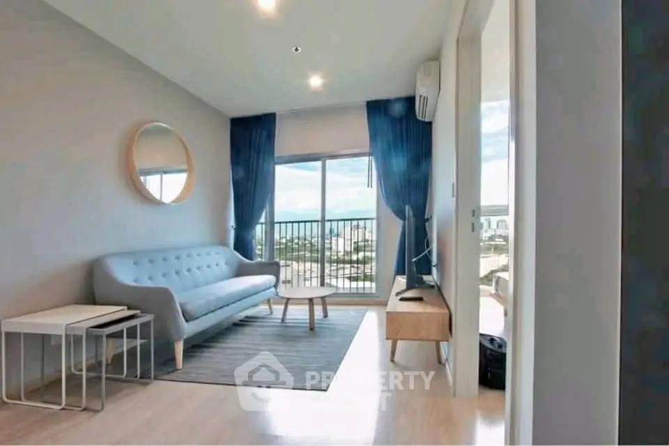 Modern living room with stylish furniture and balcony view in a high-rise apartment.