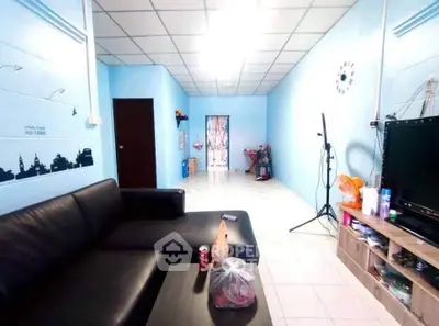 Spacious living room with modern black sofa and entertainment setup in a cozy home.