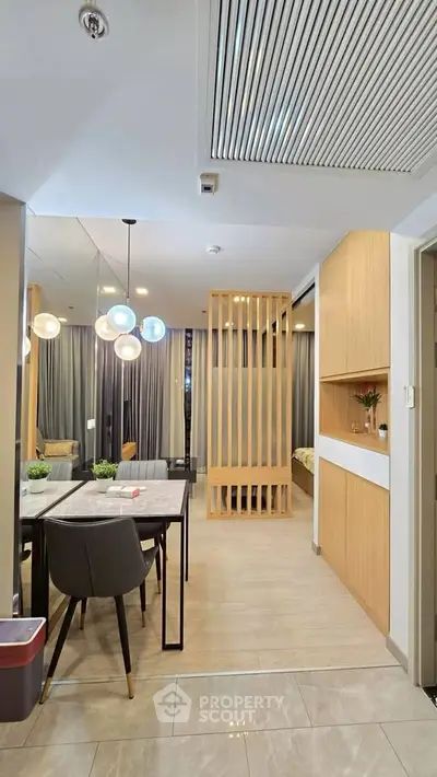 Modern open-plan living area with stylish dining set and contemporary lighting in a chic apartment.