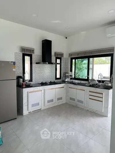 Modern kitchen with sleek design, featuring gas stove and large windows for natural light.