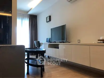 Modern living room with sleek TV setup and stylish furniture in a bright apartment.