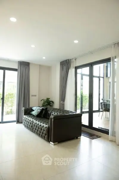 Spacious modern living room with elegant sofa and large windows for natural light.