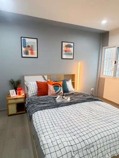 Modern bedroom with stylish decor and cozy ambiance, featuring colorful pillows and contemporary artwork.