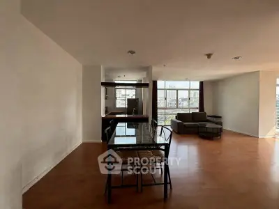 Spacious open-plan living room with modern furniture and large windows offering city views.