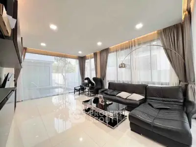 Luxurious modern living room with sleek black leather furniture and large windows overlooking a pool.