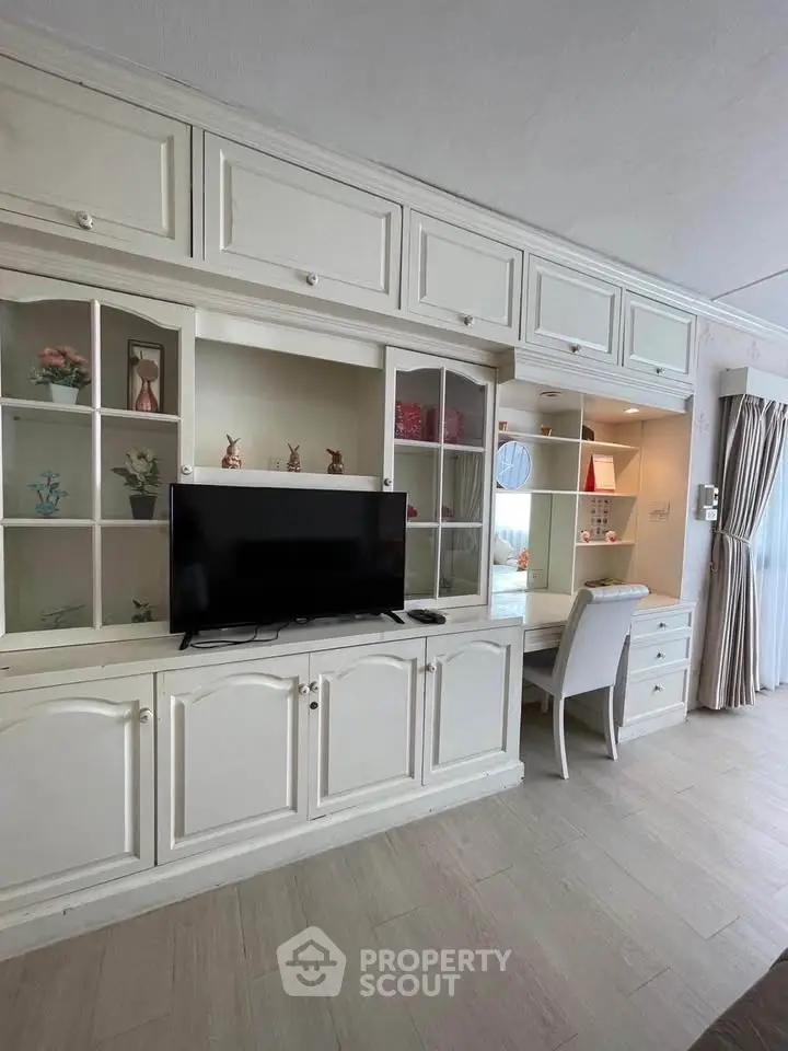 Elegant living room with built-in shelving and TV, featuring a cozy study nook.