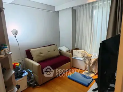 Cozy small living room with sofa, fan, and natural light