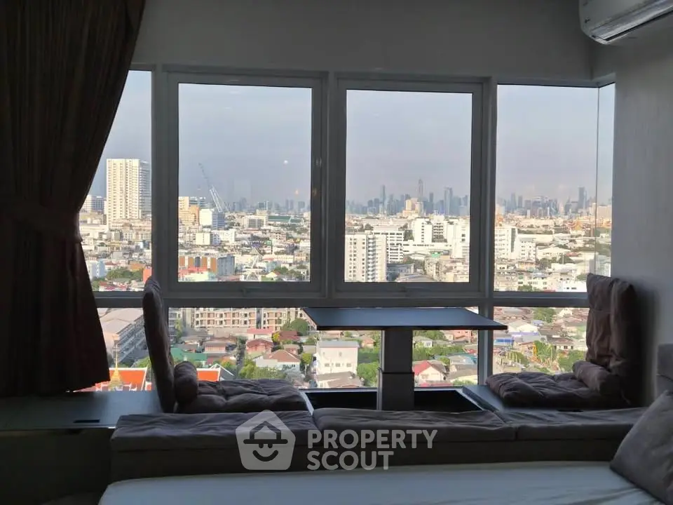 Stunning city view from a cozy living room with large windows and comfortable seating.