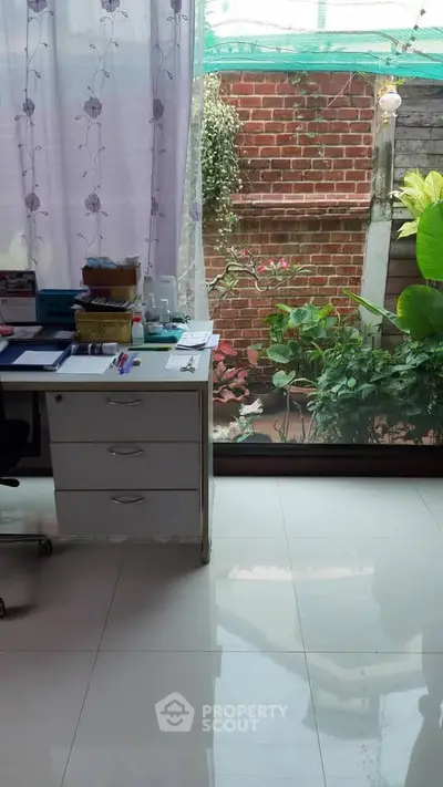 Charming home office with garden view through large window, perfect for productivity and relaxation.